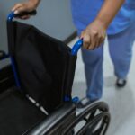 woman pushing empty wheelchair in medical environment