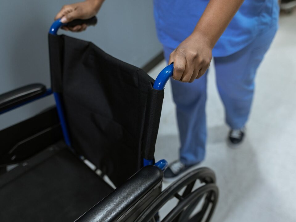 woman pushing empty wheelchair in medical environment